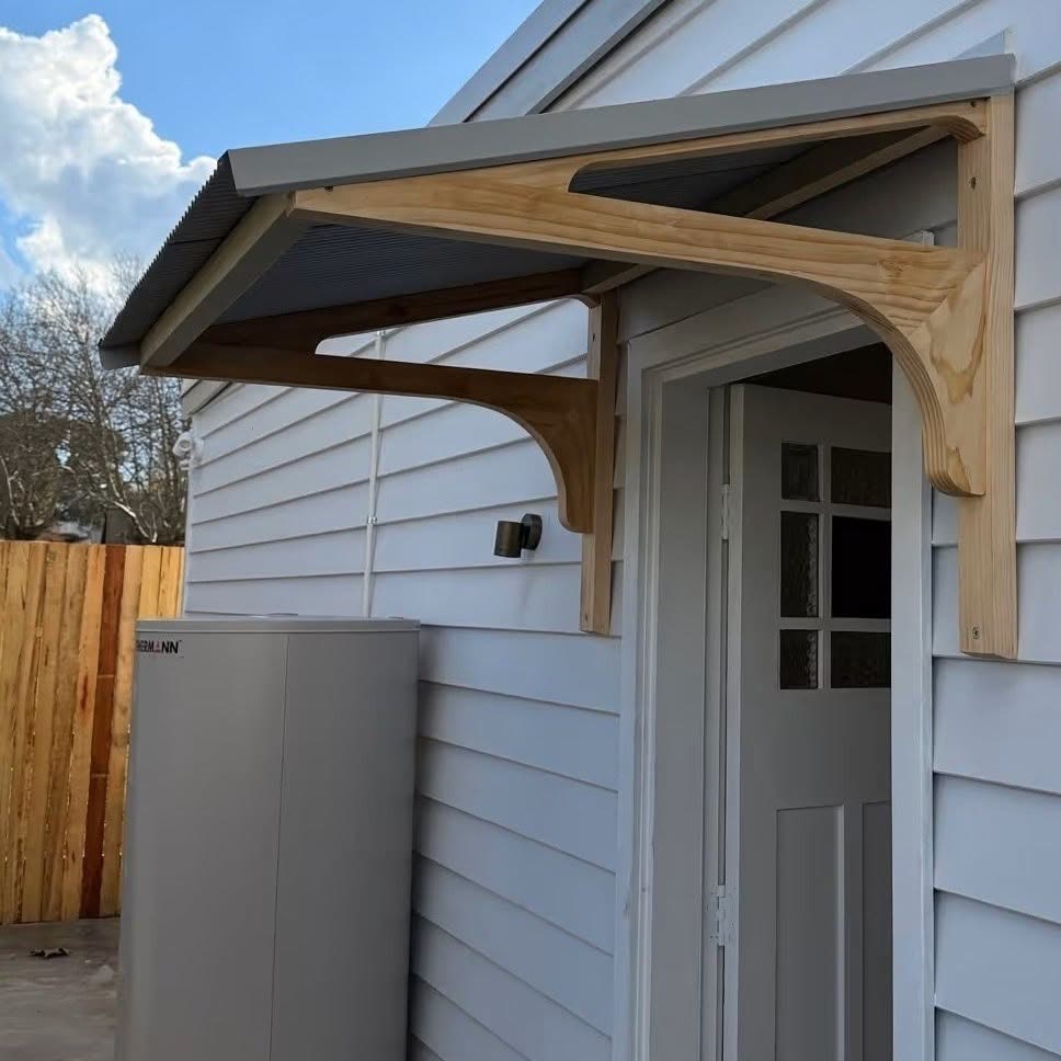 A timber-framed awning built over a back door on a weatherboard house