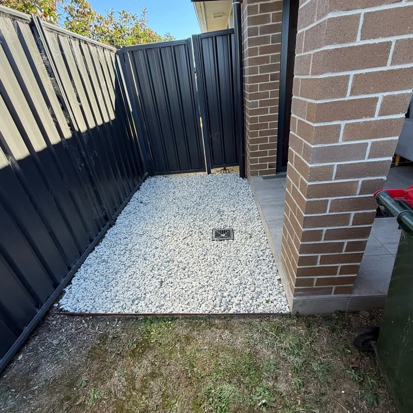 A tidy gravelled garden bed between a fence and a brick wall